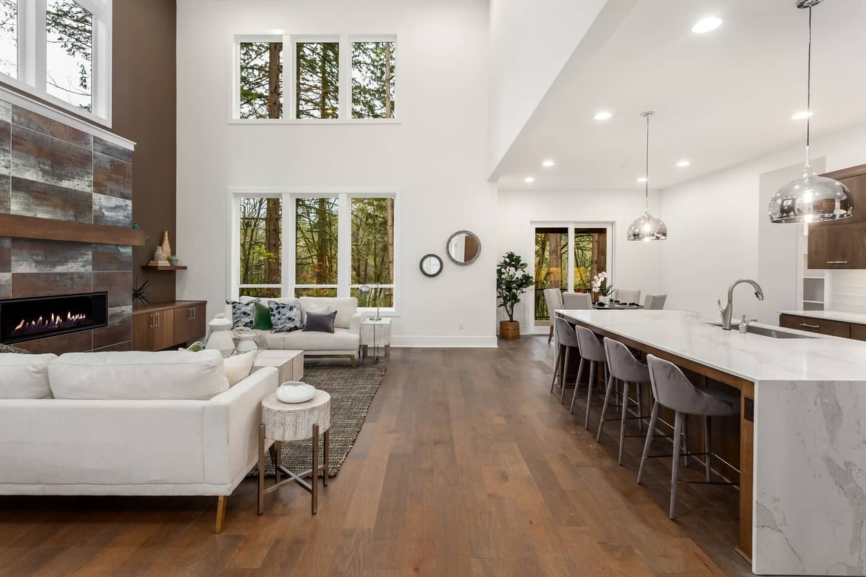 Open-Concept Living Room Interior Painting Bright open-concept living room with crisp white walls, vaulted ceiling, linear fireplace, and kitchen island — interior house painting Middlesex County