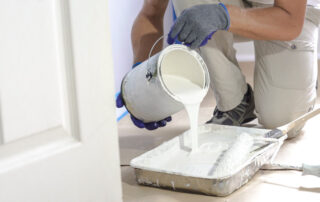 Man Pours Paint Into The Tray And Dips Roller.