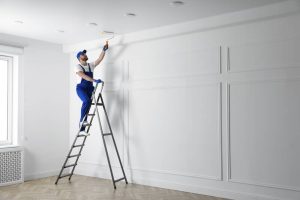 Handyman Painting Ceiling With White Dye Indoors