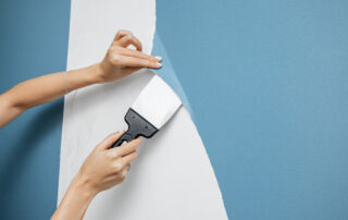 A Woman Housewife Peels Off An Old Vinyl Wallpaper With Scraper