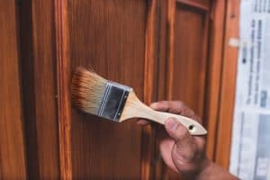 A Handyman Paints A Fresh Coat Of Varnish On The Door
