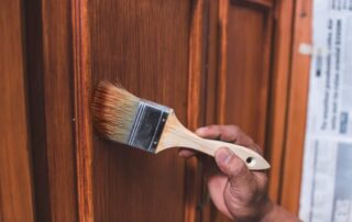 A Handyman Paints A Fresh Coat Of Varnish On The Door