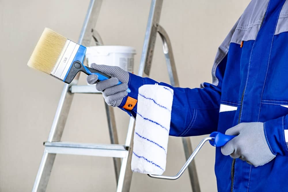 Painter in A Blue suit holding a paint brush and roller