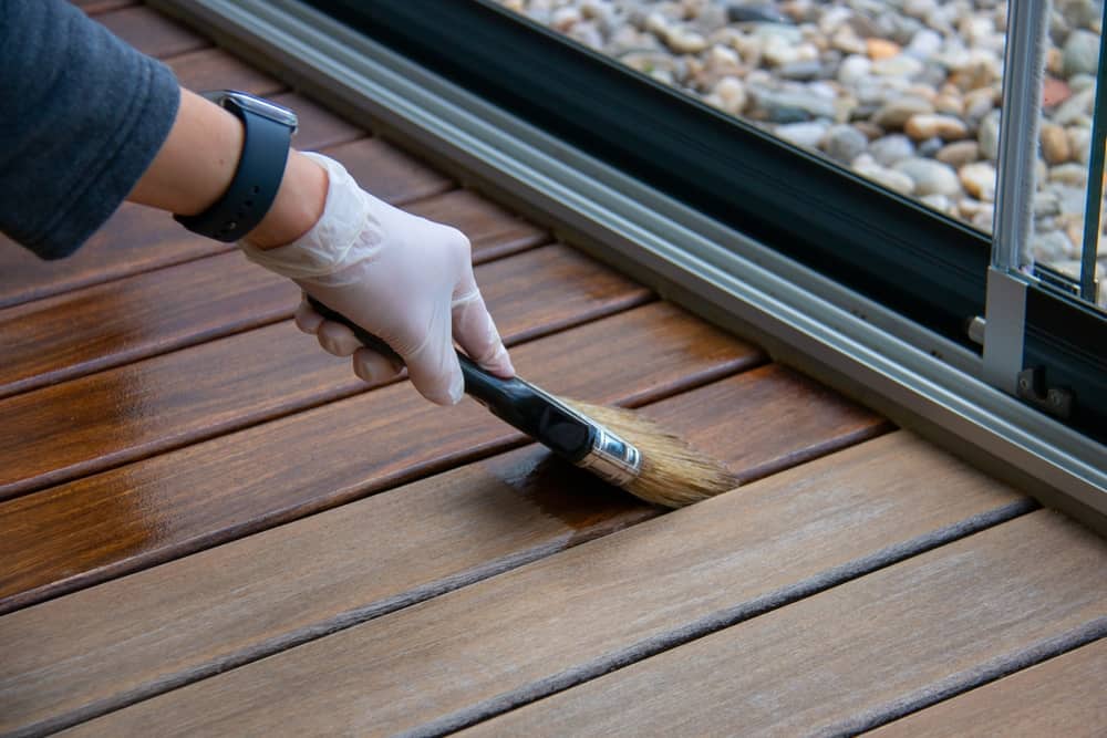 Worker Applying Deck Oil On Decking Boards With Deck Staining