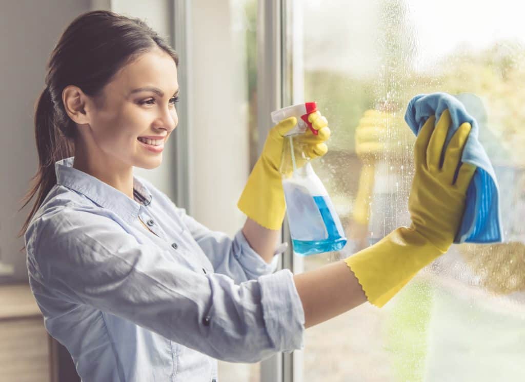 women cleaning glass window with rubber gloves.