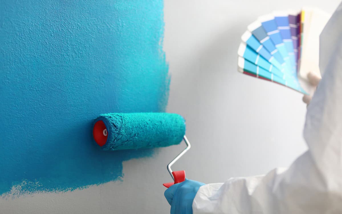 Master painter holds in his hands color palette with shades of blue