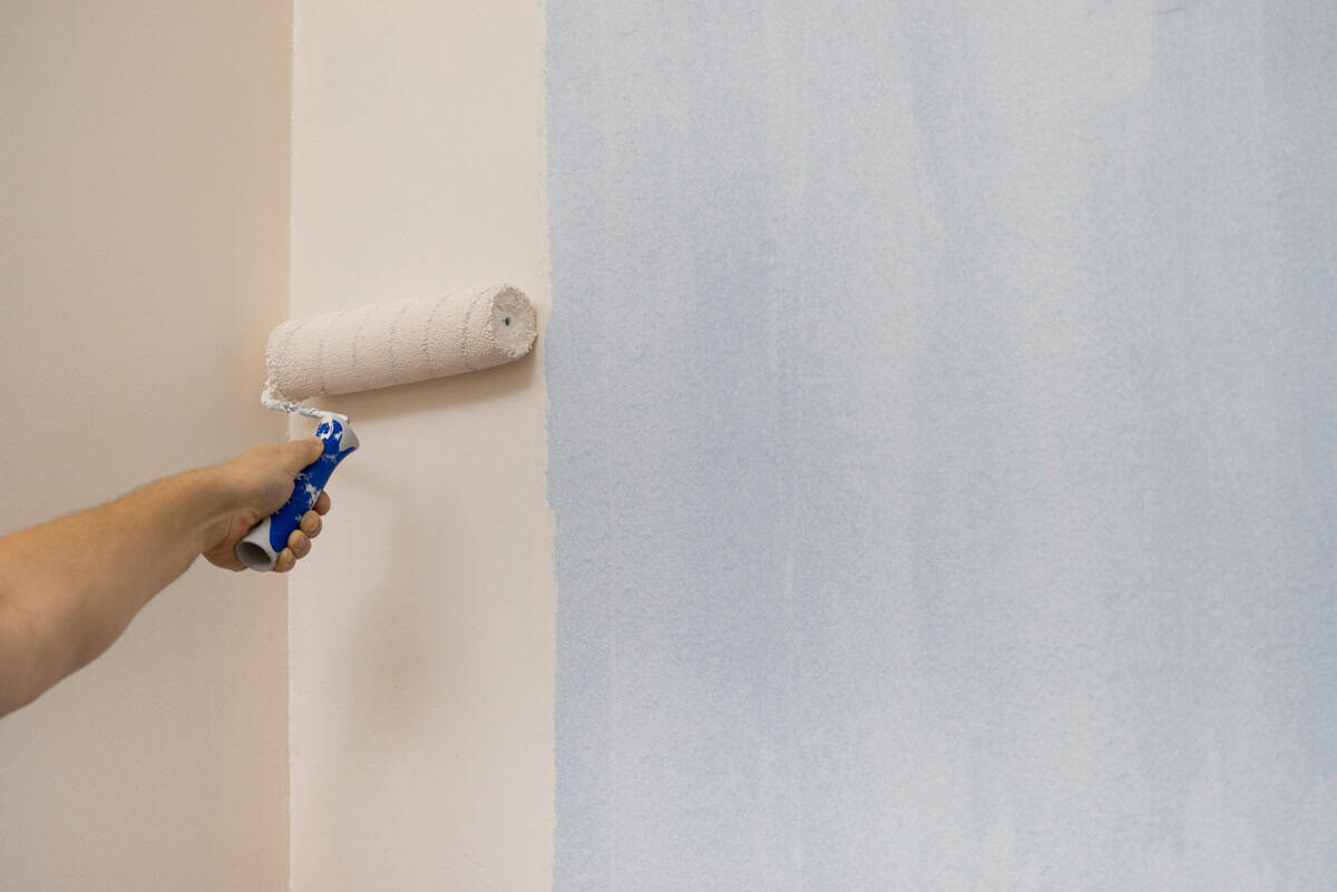 Person applying paint on wall