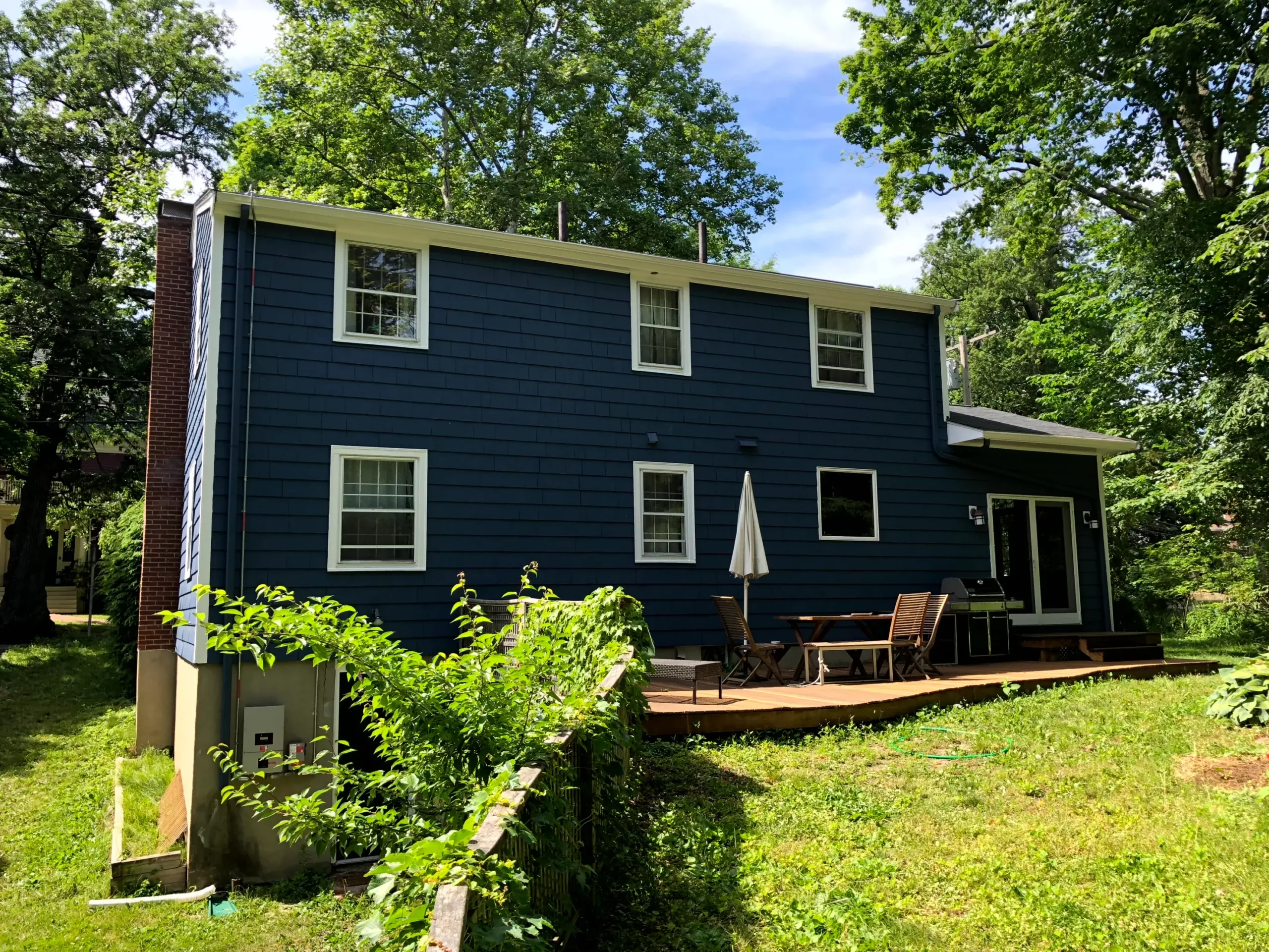 IMG_1094 Rear view of a residential home with fresh blue exterior paint, white trim, and a wooden deck.
