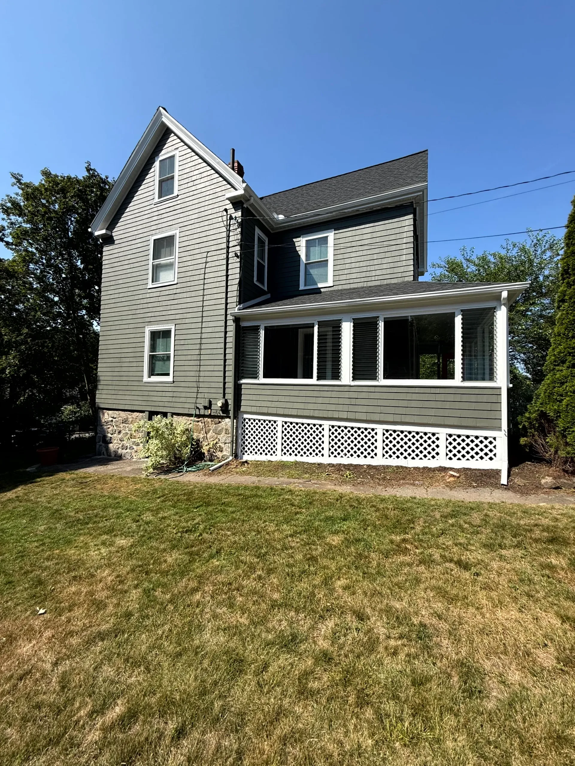 Professional exterior house painting with green siding Side view of a residential home showcasing expertly applied green exterior paint and white trim.